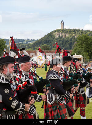 Scottish pipers playing bagpipes at the Stirling Highland games The National Wallace Monument, Stirling in Scotland