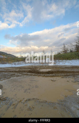 A puddle on a dirt road in late autumn, Sakhalin Island, Russia. Stock Photo