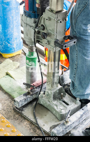 Worker drilling holes in concrete floor at construction site Stock Photo