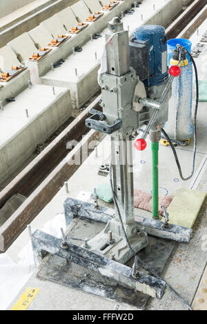 Worker drilling holes in concrete floor at construction site Stock Photo