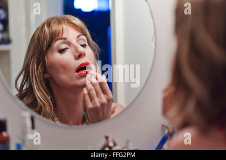 Mature woman applying lipstick. Stock Photo