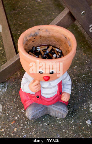 A terracotta pot being used as a ashtray Stock Photo