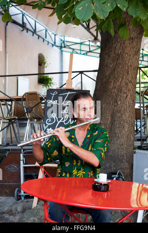 Flute player at red table under a tree  in Provence France Europe Stock Photo