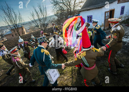 Koliadnyky - group of adult and kids dressed in costumes of soldiers and traditional Ukrainian female costumes - dance in a ring at the yard of the host house during Malanka celebration in Velykyj Kuchuriv village, Bukovina, Ukraine Stock Photo