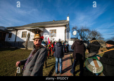 Villager dressed as Jew walks with group of Koliadnyky - group of male adult and kids dressed in costumes of soldiers and traditional Ukrainian female costumes during Malanka celebration in Velykyj Kuchuriv village, Bukovina, Ukraine Stock Photo