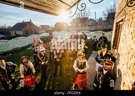 Koliadnyky - group of adult and kids dressed in costumes of soldiers and traditional Ukrainian female costumes - sing carols (koliadky) during Malanka celebration in Velykyj Kuchuriv village, Bukovina, Ukraine Stock Photo