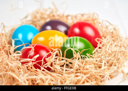 Closeup of isolated easter nest of straw with different colored easter eggs. Stock Photo