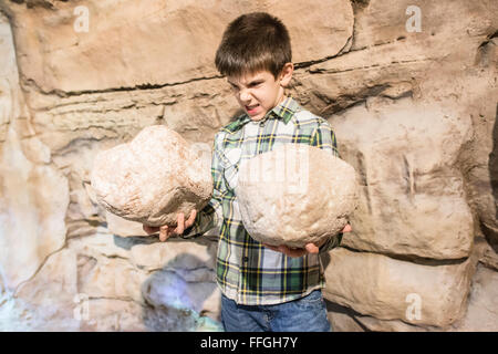 Strong child holds heavy stones. Stock Photo