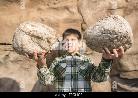 Strong child holds heavy stones. Stock Photo