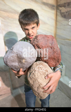 Strong child holds heavy stones. Stock Photo