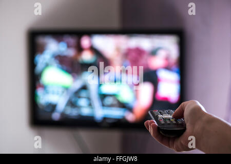 TV and remote control. Hand hold remote. Stock Photo