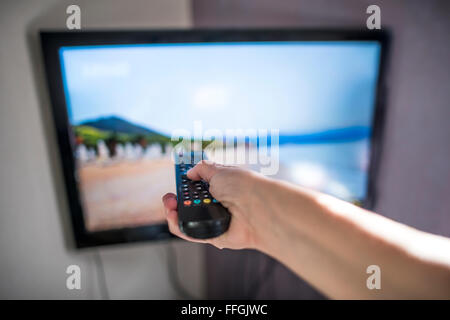 TV and remote control. Hand hold remote. Stock Photo