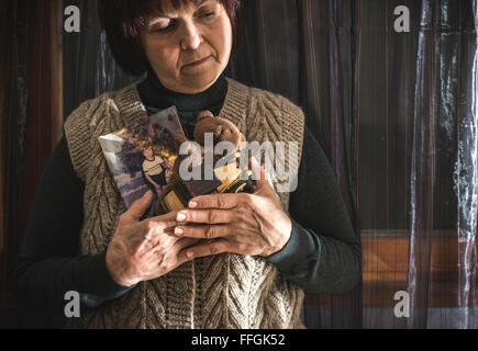 Senior woman hold pictures of childrens. Toys Stock Photo