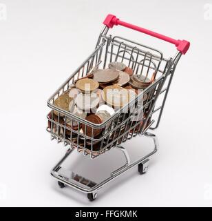 Small supermarket shopping trolley with coins inside. Cost of living concept Stock Photo