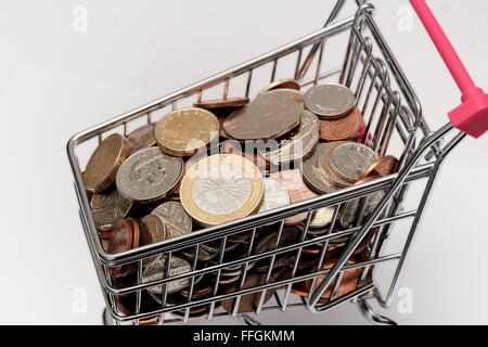 Small supermarket shopping trolley with coins inside. Cost of living concept Stock Photo