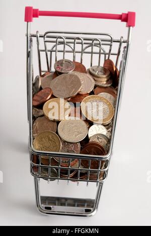 Small supermarket shopping trolley with coins inside. Cost of living concept Stock Photo