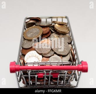 Small supermarket shopping trolley with coins inside. Cost of living concept Stock Photo