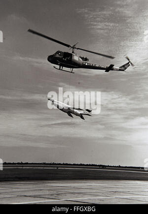 An Air Force UH-1H helicopter from Tyndall Air Force Base, Fla., lowers a jet drone to the ground after recovery of the test drone from the Gulf of Mexico in1969. Stock Photo