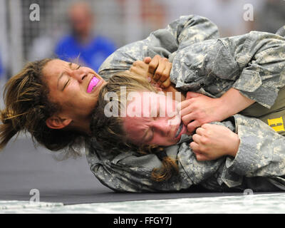 Army 1st Lt. Courtney Olofsson (front right) tries to escape a choke hold by Staff Sgt. Alyssa Johnson during the opening round of the 2012 U.S. Army Combatives Championship. Olofsson is from Fort Lewis, Washington, and Johnson is from Fort Drum, New York. Stock Photo