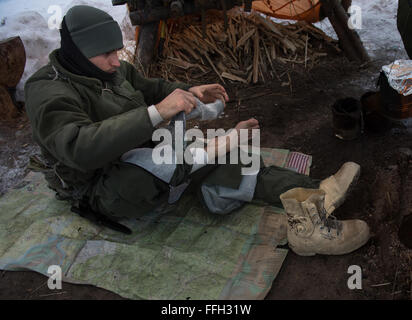 U.S. Air Force 1st Lt. Evan Wells, 37th Helicopter Squadron, UH-1N Huey pilot, changes socks during arctic survival training to prevent hypothermia and soggy boots. During the training, students learned the basic principles of retrieving food, creating water and building shelter. The course is five days in duration with instruction in familiarization with the arctic environment, medical, personal protection, sustenance and signaling.