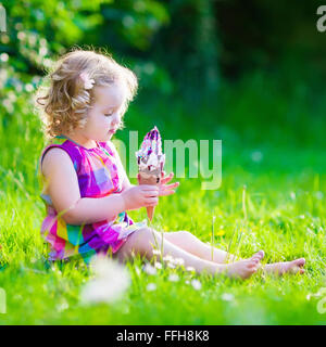 Child eating ice cream. Kids play outdoors enjoying sweet snack on a hot summer day. Children eat icecream. Stock Photo