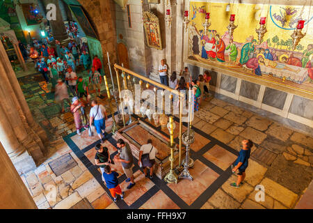 People around Stone of Anointing and mosaic icon on the wall at the entrance to Holy Sepulcher Church in Jerusalem. Stock Photo