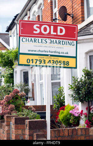 The marketing for sale sign boards of local estate agent Charles Harding outside homes on a street in Swindon Wiltshire UK Stock Photo