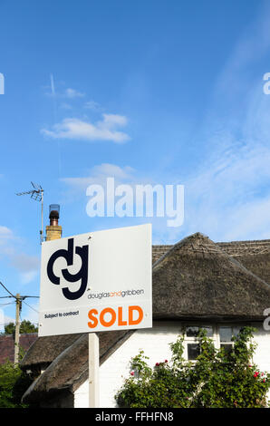 An estate agents sign outside a thatched cottage in Uffington, Oxfordshire, England, UK. Stock Photo