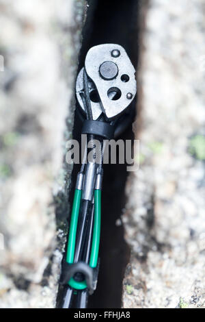 Close up view of a climbing friend gear, also known as spring-loaded camming device (SLCD) inserted in granite rock. Stock Photo