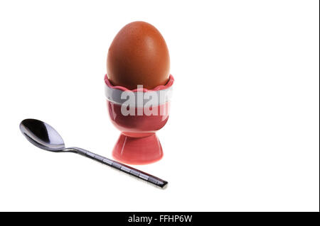 Boiled chicken egg in a glazed pottery egg cup with spoon. Stock Photo