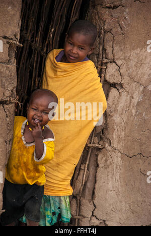 Two Masai Children in the doorway of a mud hut in a village in the Masai Mara, Kenya, Africa