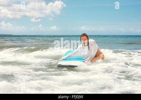 Girl on the waves in the ocean with her Surfboard. Stock image Stock Photo