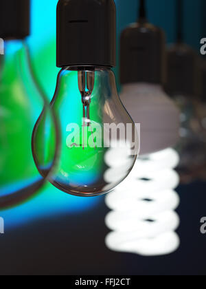 Old-fashioned incandescent light bulb among glowing energy efficient one Stock Photo