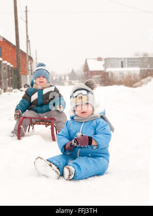 two boys sliding with sledding in the snow Stock Photo