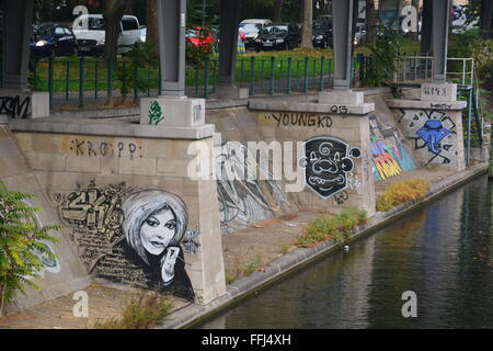 Close up of graffiti on a concrete bank and train track support along a canal near a train stop in Berlin, Germany. Stock Photo