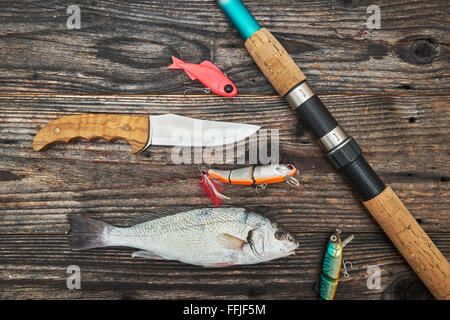 Spinning rod, reel and fishing baits isolated on wooden background, top view Stock Photo