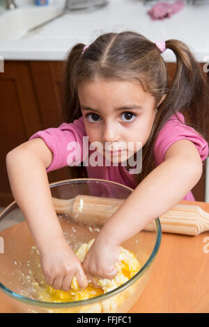 Lovely little girl kneading dough Stock Photo