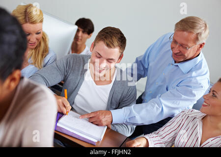 Teacher helping some students in university class Stock Photo