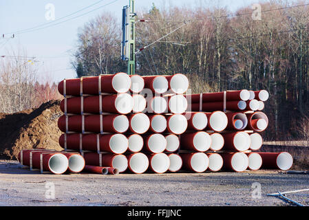 A batch of newly manufactured pipes or tubes with red on the outside and white on the inside. Electric wires for the railroad an Stock Photo