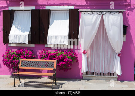 A house with locally handmade lace window blinds and draped lace over a front door in Burano, a small fishing village and tiny port on an island in Stock Photo