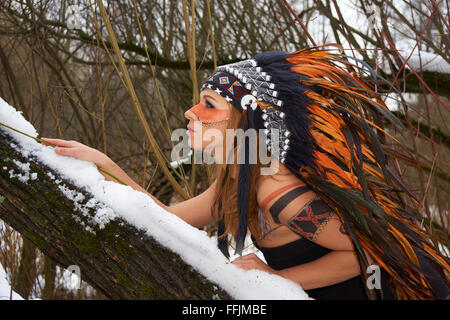 Girl in native american headdress climbs tree Stock Photo