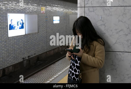 Japanese people on platform, traveling on train, Tokyo, Japan, Asia. Young woman with mobile phone in subway underground station Stock Photo