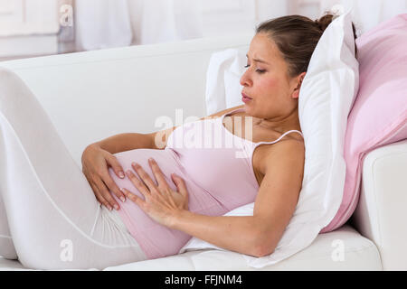 Pregnant woman getting a contraction at home in the living room Stock Photo