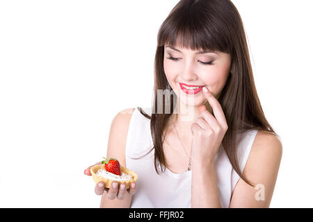 Young smiling woman holding in her palm delicious strawberry tart cake in dough basket, beautiful cheerful female teen model Stock Photo