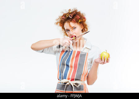 Housewife holding knife and eating apple isolated on a white background Stock Photo