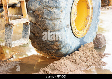 Close up detail of a front loader wheel standing in mud and water. Stock Photo