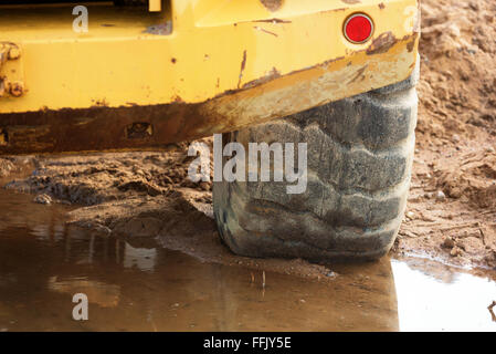 Close up detail of a front loader wheel standing in mud and water. Stock Photo