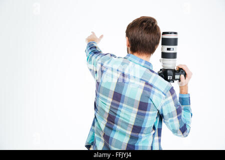 Back view portrait of a male photographer holding photo camera and pointing on something isolated on a white background Stock Photo