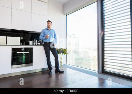 Businessman in apartment having a coffee break Stock Photo