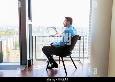 Businessman in apartment using laptop computer Stock Photo